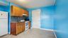Kitchenette featuring wood-finish cabinetry, a patterned tile backsplash, stainless steel sink, and white appliances