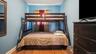 Bedroom featuring light blue walls, wood-finish flooring, and a window with red and white curtain panels