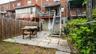 Rear exterior featuring a paver patio, wood privacy fence, and multi-level outdoor access stairs