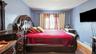Bedroom featuring wood-finish flooring, a wall-mounted television, and baseboard registers