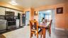 Kitchen and dining area featuring light gray cabinetry, stainless steel appliances, a gray mosaic tile backsplash, and light-toned floor tiling