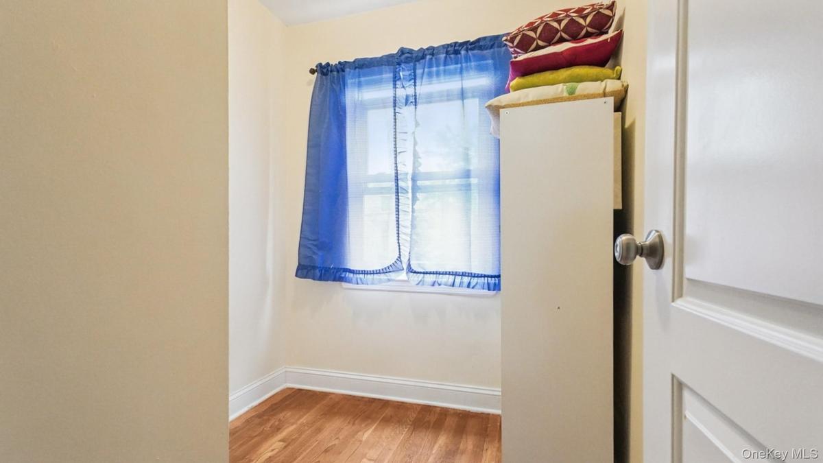 Room featuring wood-finish flooring, light-toned wall paint, and white baseboards