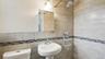 Bathroom featuring full-height tiled walls, a decorative mosaic tile accent band, and a rainfall showerhead