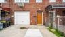 Brick facade featuring a panel garage door, light wood-finish entry door, and a concrete driveway