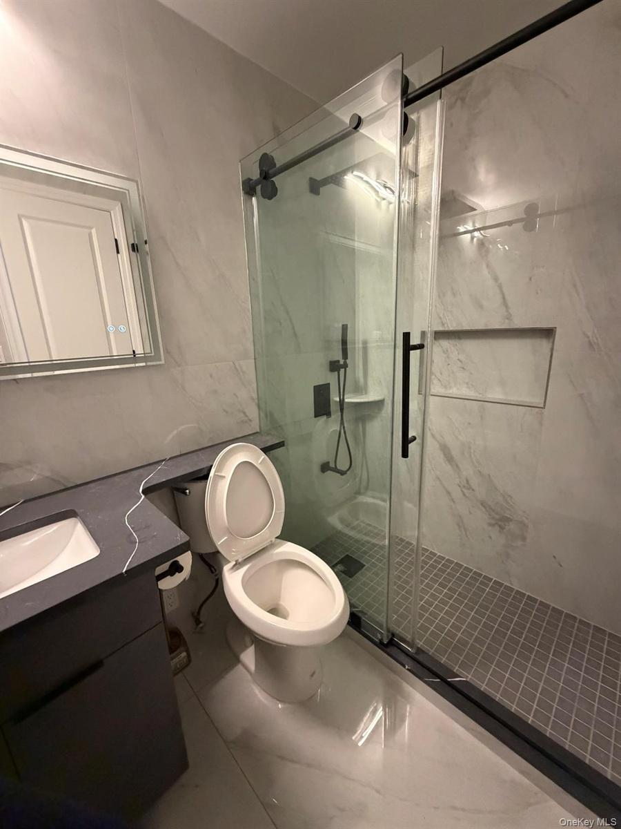 Bathroom with vanity and a marble finish shower