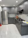 Kitchen with dark countertops, gray cabinetry, freestanding refrigerator, tasteful backsplash, and under cabinet range hood