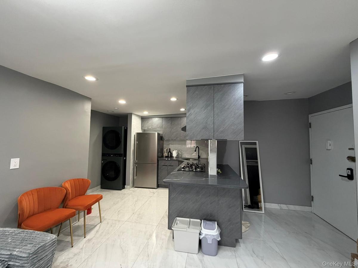 Kitchen with a peninsula, gray cabinets, appliances with stainless steel finishes, recessed lighting, and dark countertops