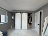 Bedroom with a barn door, light marble finish flooring, ensuite bathroom, a spacious closet, and a baseboard heating unit