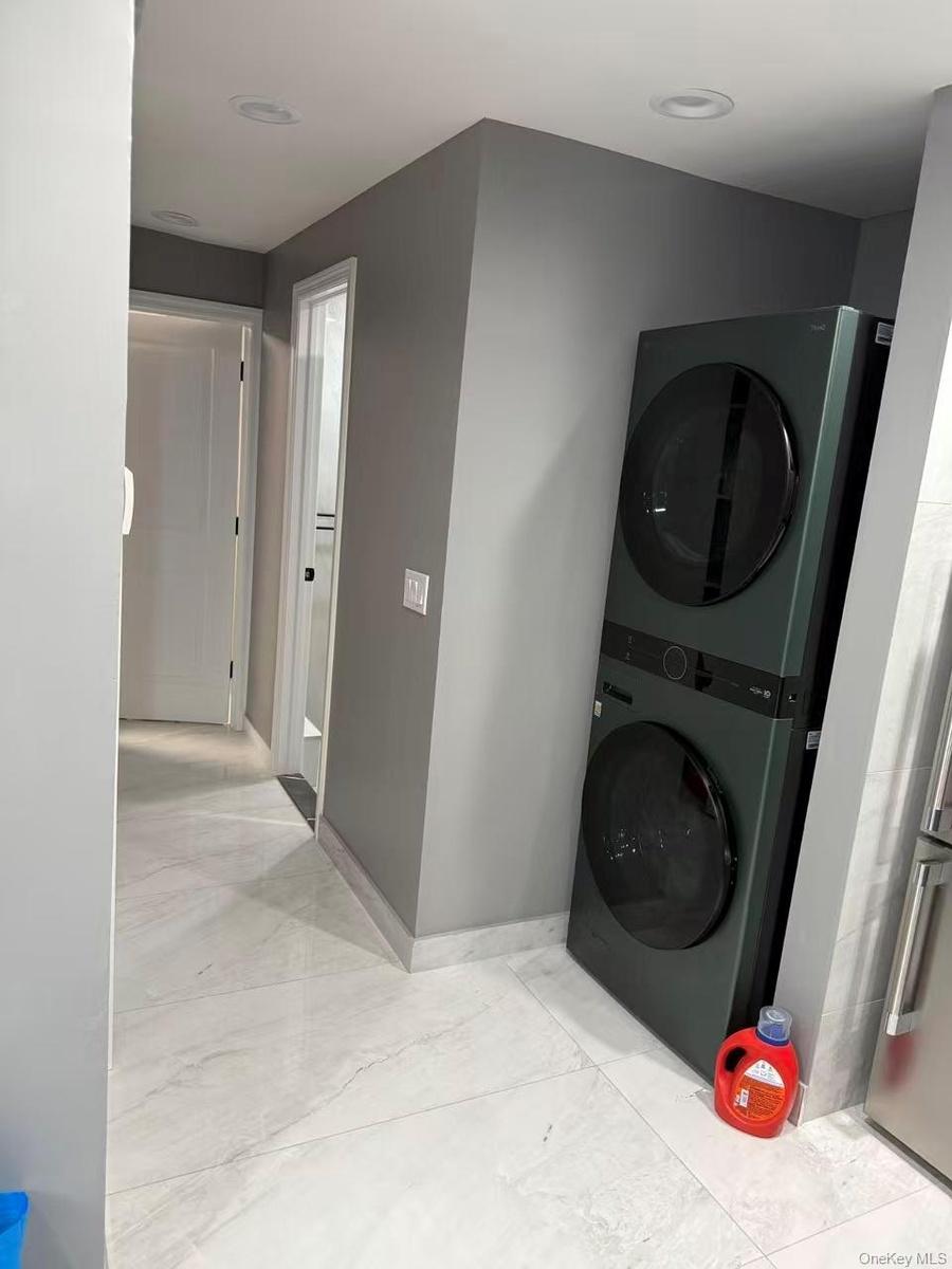 Washroom with stacked washer / drying machine and baseboards