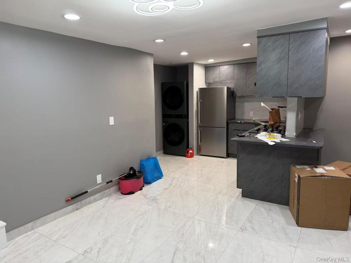 Kitchen with dark countertops, recessed lighting, a peninsula, freestanding refrigerator, and gray cabinetry