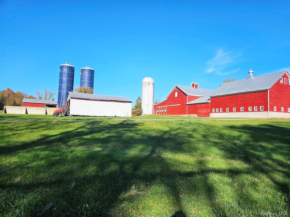 View of farm featuring barns, silos and a pole building