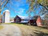 View of barn with dirt driveway and a lawn