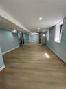 Spacious basement featuring wood finish flooring, recessed lighting, light blue painted walls, and white trim