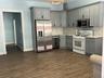 Kitchen featuring light gray shaker-style cabinetry, a white countertop, and a full-height backsplash living area combined
