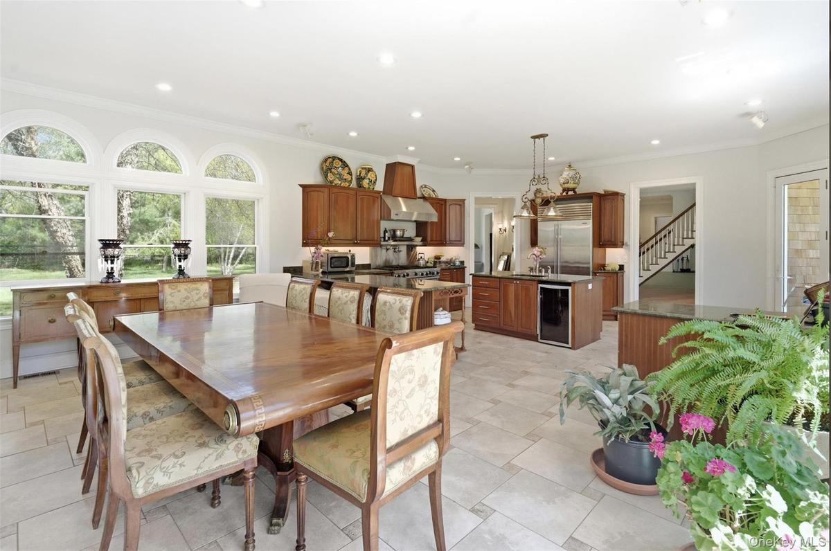 Spacious kitchen and dining area featuring light-toned tile flooring, recessed lighting, and a bay window with arched transoms