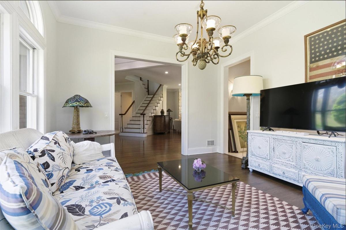 Living area featuring dark wood-finish flooring, white trim, and a decorative chandelier