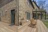 Expansive wood-finish deck with cedar shake siding, multiple exterior access points, and a covered patio area below a second-story balcony