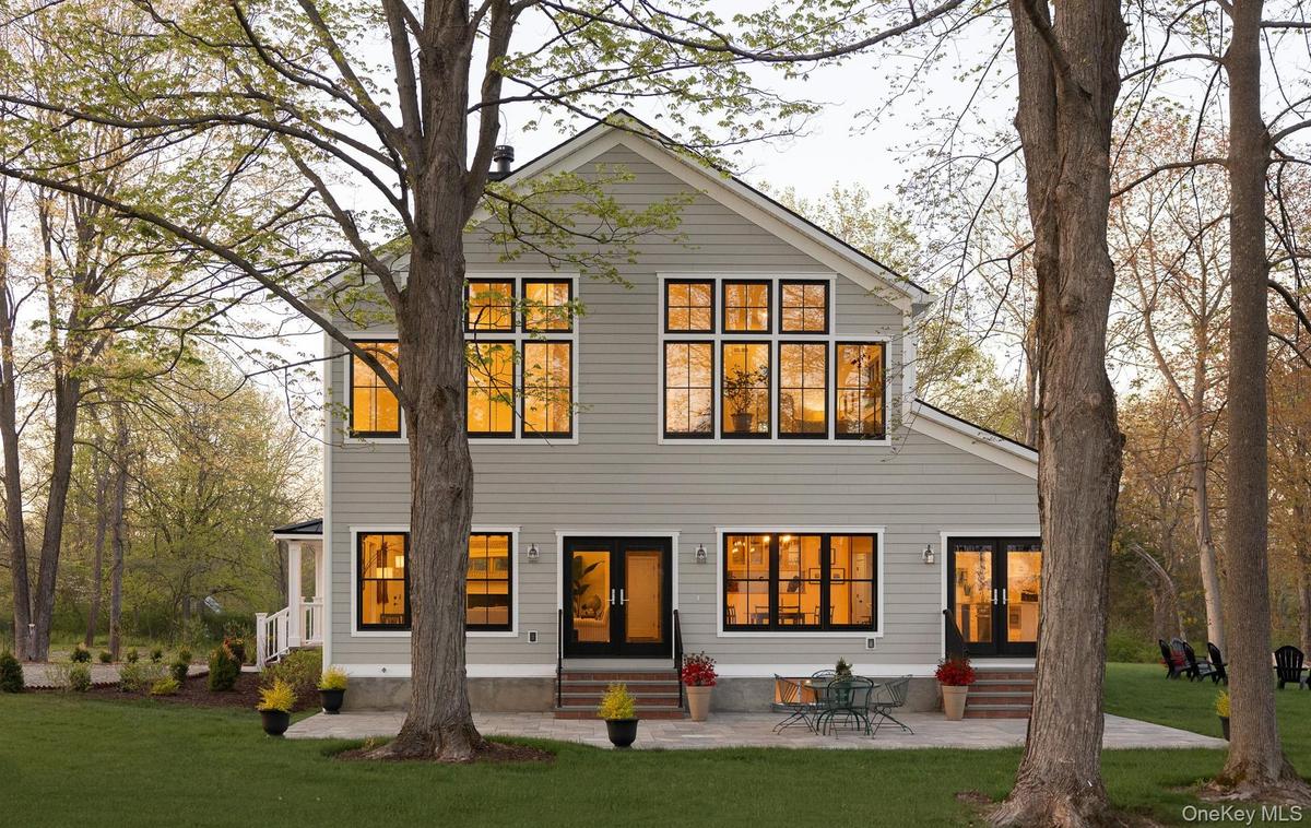 Southern side of the home with patio, two sets of patio doors, and extensive windows