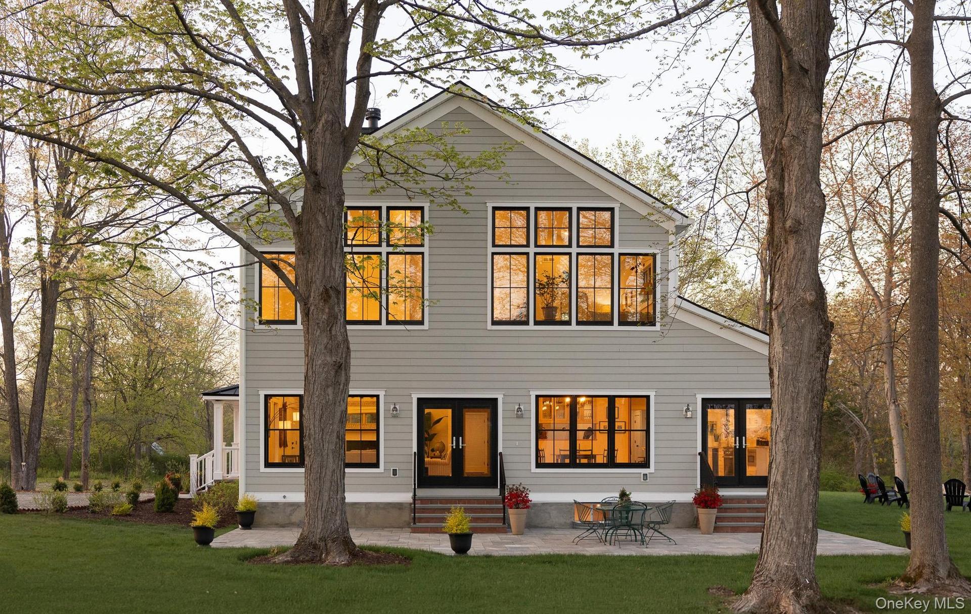 Southern side of the home with patio, two sets of patio doors, and extensive windows