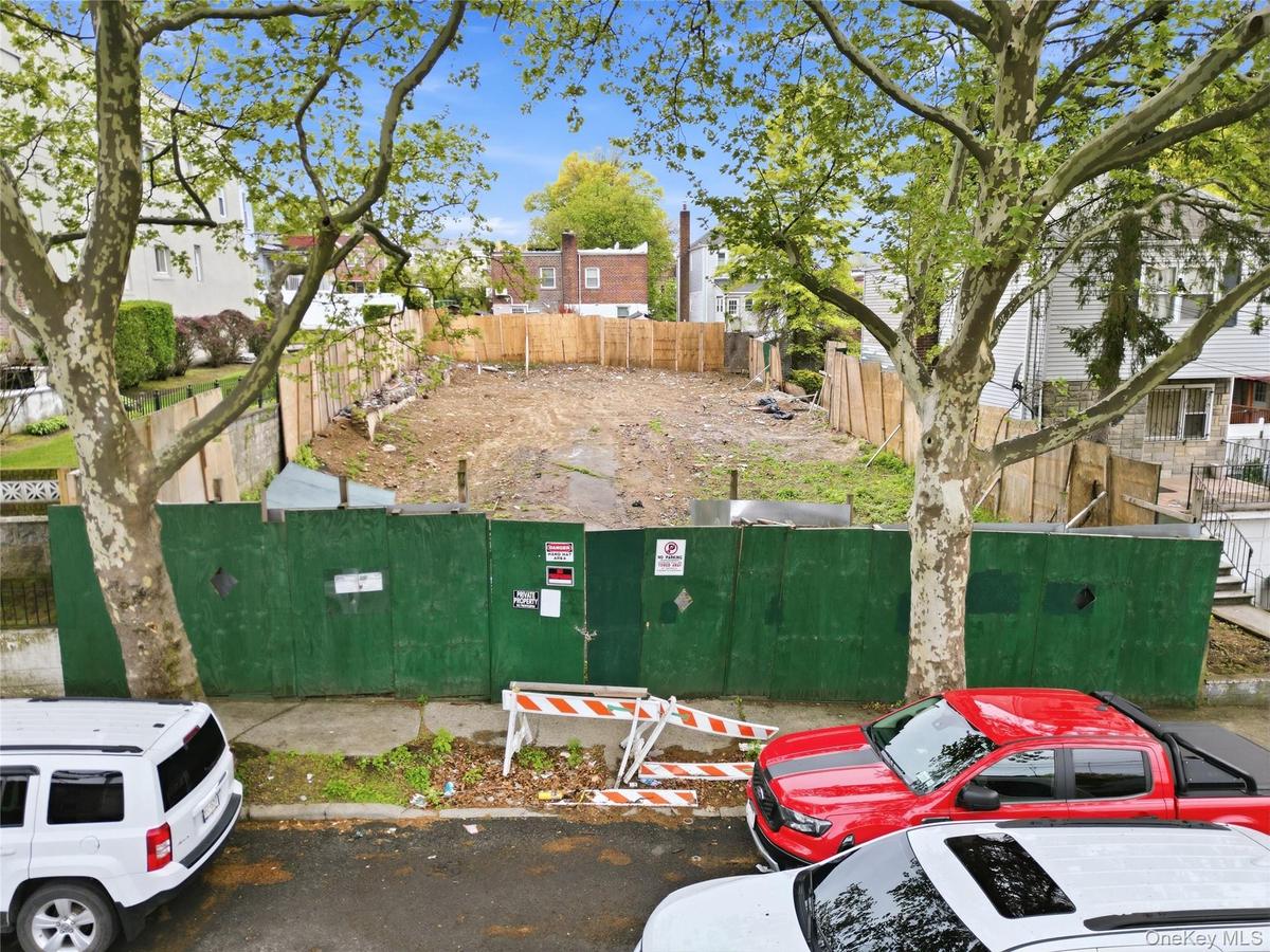 Cleared lot featuring a combination of green construction fencing and a wood-panel fence