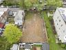 Cleared lot with surrounding residential structures and street parking visible
