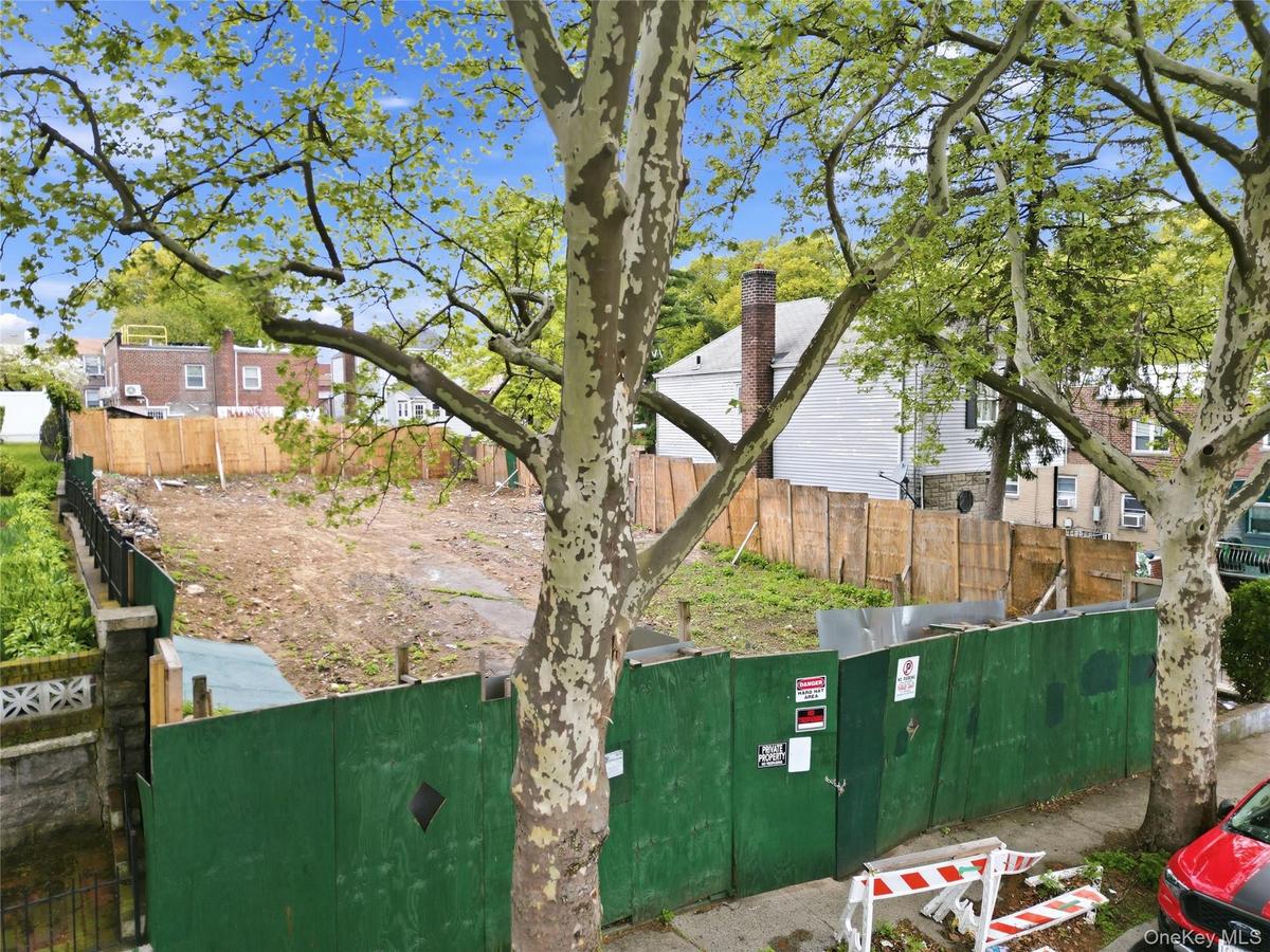 Cleared lot featuring a combination of green construction fencing and a wood-panel fence