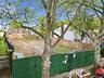 Cleared lot featuring a combination of green construction fencing and a wood-panel fence