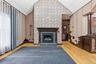 Vaulted ceiling room featuring a gas fireplace with a dark wood mantel and slate hearth, patterned wall paneling, light wood-finish flooring, and a co