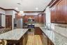 Kitchen featuring wood-finish cabinetry, granite countertops, stainless steel appliances, a center island, and wood-finish flooring