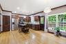 Open-concept kitchen and living area featuring wood-finish flooring, dark wood cabinetry, stainless steel appliances, and a large window with exterior