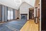 Vaulted ceiling with an elegant circular light fixture, hardwood flooring, and a fireplace featuring a dark wood mantle and stone surround