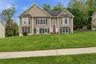 Two-story residence featuring tan siding and a dark roof
