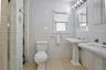Bathroom featuring two pedestal sinks, a toilet, and a glass-enclosed shower