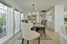 Dining area featuring large grid-pattern windows, a rustic wood-finish dining table, and tile flooring