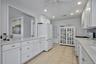 Kitchen featuring white cabinetry, light-toned countertops, recessed lighting, tile flooring, and an architectural opening