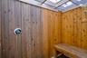 Wood-paneled outdoor shower featuring a built-in wooden bench and a chrome shower fixture