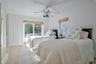 Bright room featuring neutral-toned tile flooring, a white ceiling fan, and white walls