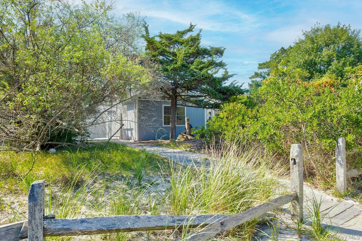Wood pathway leading to a residence with light blue siding, white trim