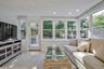 Sun-filled room featuring extensive windows, a glass-paned door, recessed lighting, white wood-plank ceiling, and light-toned tile flooring