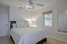 Bedroom featuring ceramic tile flooring, a window with a woven shade, a ceiling fan with integrated lighting, and white paneled doors