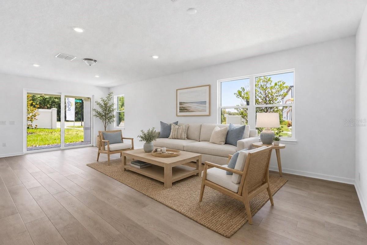 Virtually staged living space with warm wood look floors and an easy open layout.