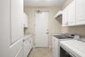 Large utility room with lots of storage, hanging space and utility sink.