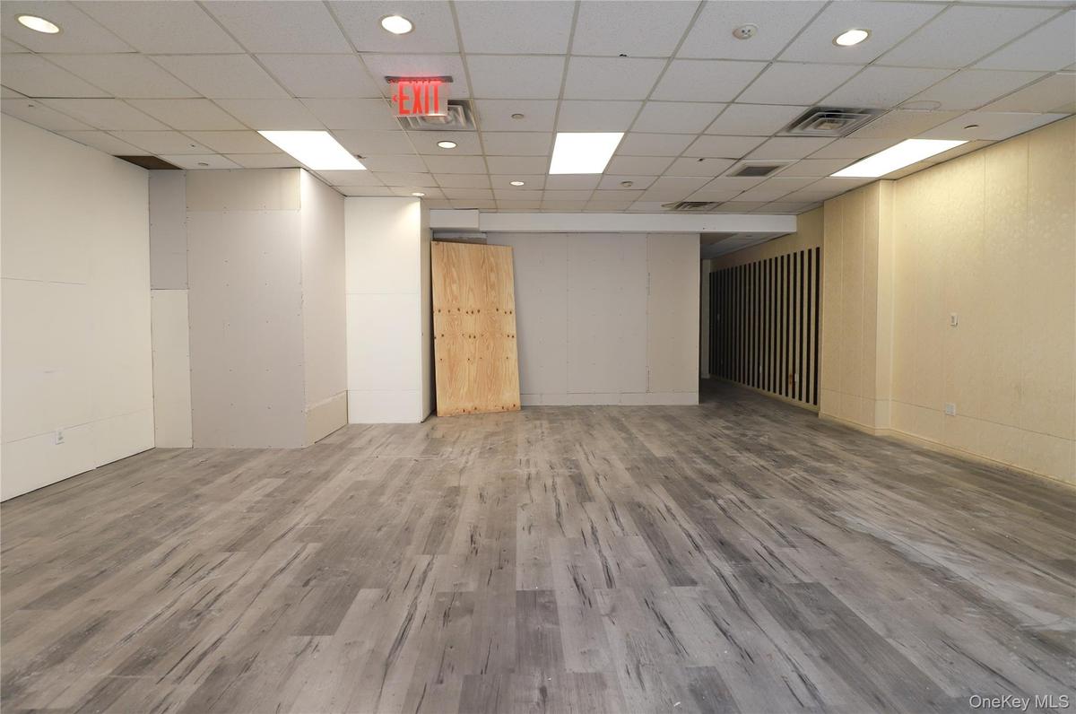 Spacious open-concept interior featuring wood-finish flooring, recessed lighting, and a suspended acoustic ceiling