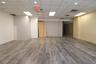 Spacious open-concept interior featuring wood-finish flooring, recessed lighting, and a suspended acoustic ceiling
