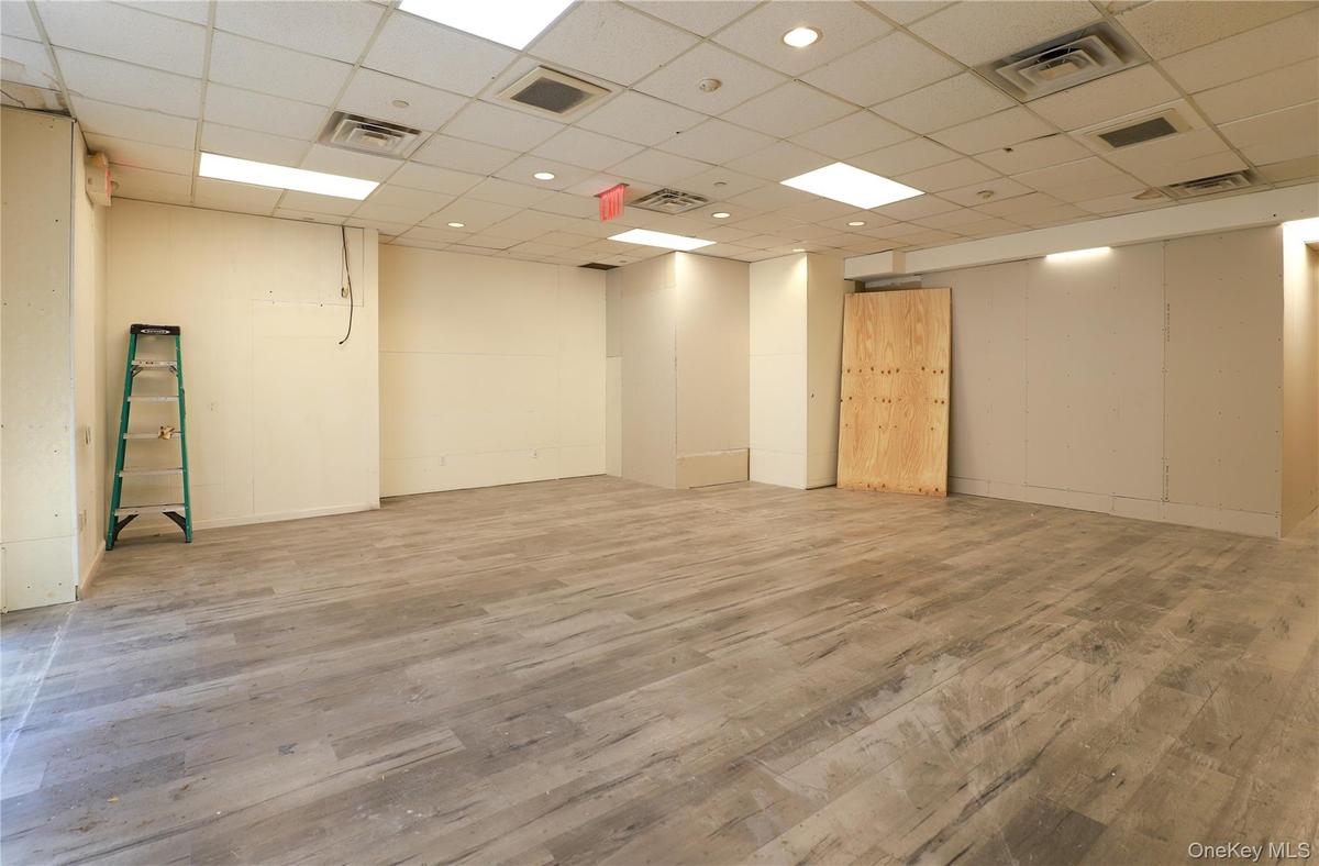 Spacious room featuring wood-finish flooring, drop ceiling with recessed lighting, and neutral wall tones