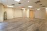 Spacious room featuring wood-finish flooring, drop ceiling with recessed lighting, and neutral wall tones