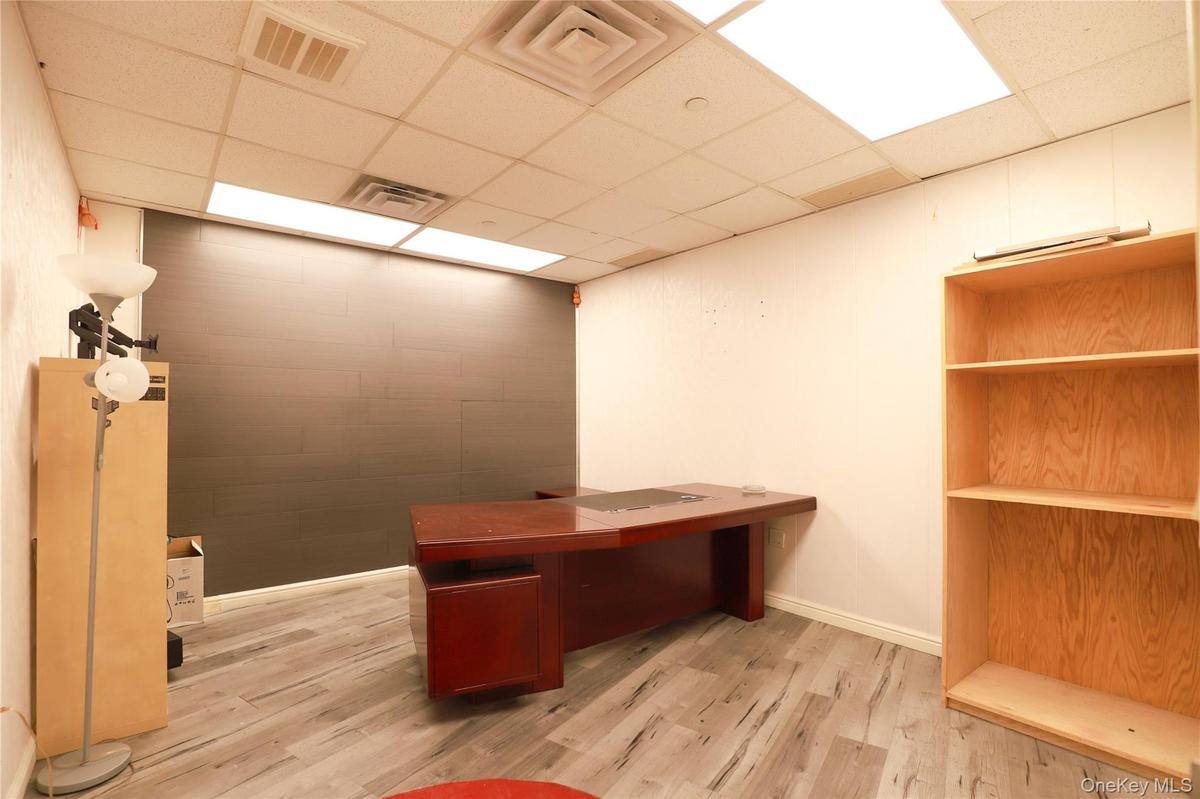 Office space featuring wood-finish flooring, white walls, and a drop-tile ceiling with integrated lighting