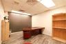 Office space featuring wood-finish flooring, white walls, and a drop-tile ceiling with integrated lighting