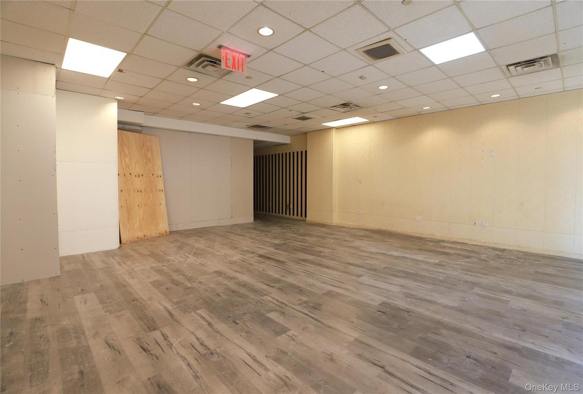 Spacious interior featuring wood-finish flooring, drop ceiling with recessed lighting, and a neutral color palette