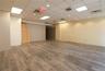 Spacious interior featuring wood-finish flooring, drop ceiling with recessed lighting, and a neutral color palette